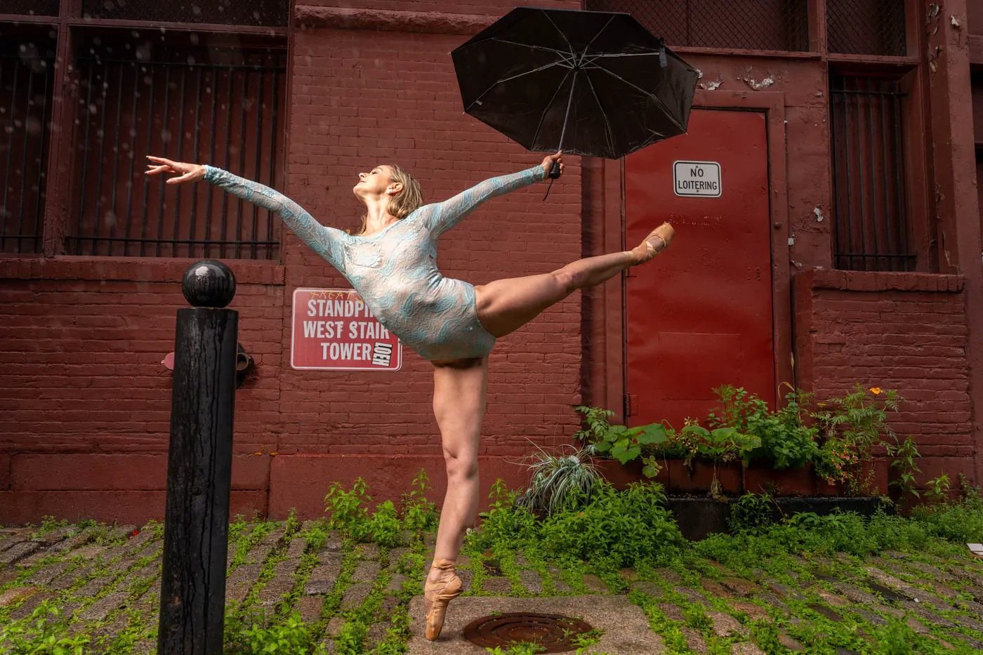 Ballet dancer arabesque with umbrella in the rain