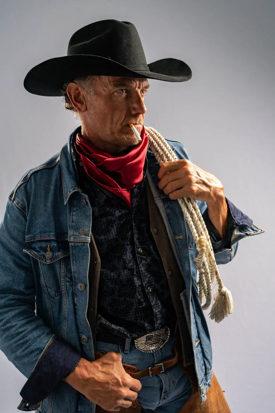 Studio portrait of a cowboy with a rope and red bandana