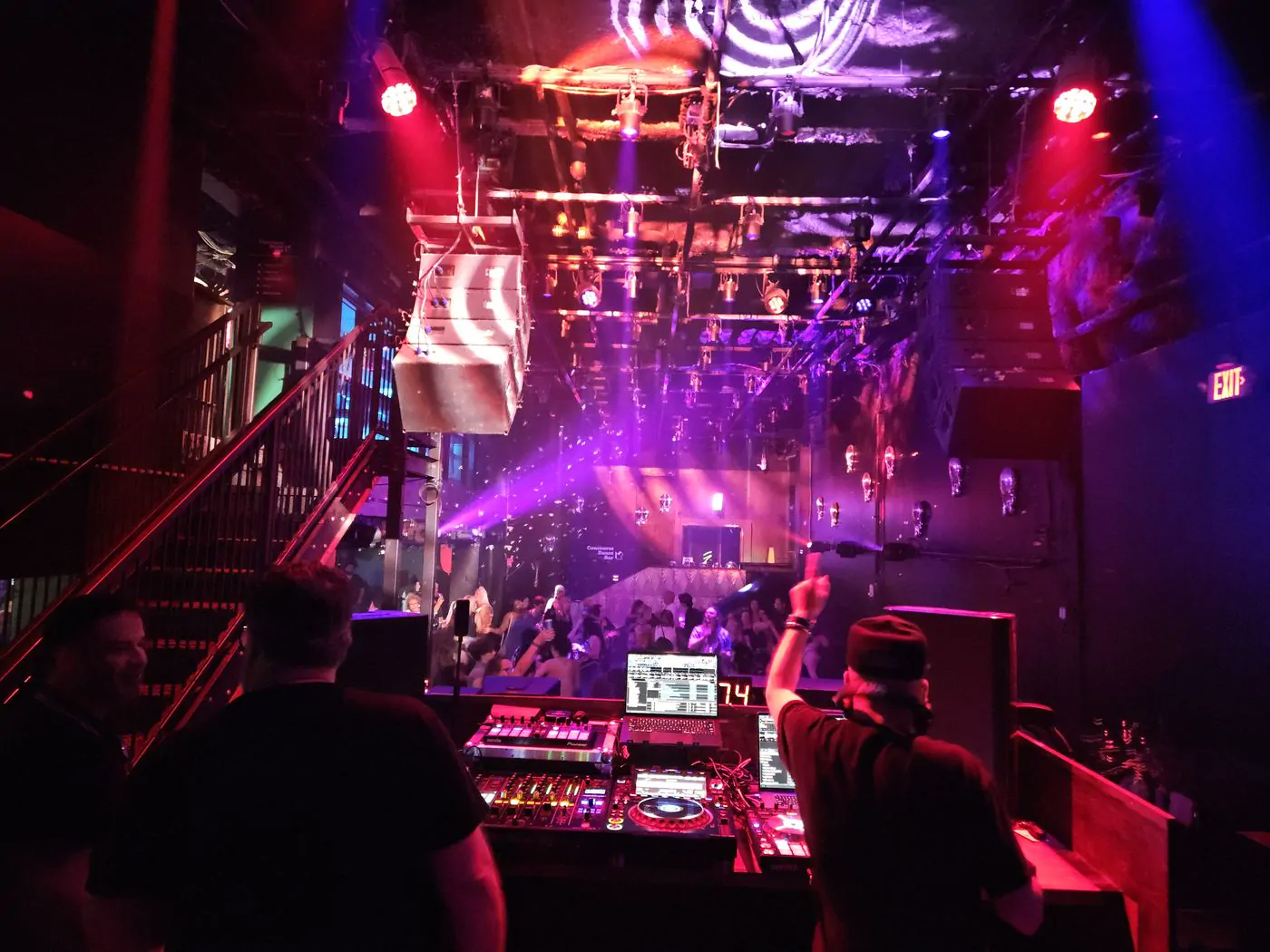 DJ performing for a packed nightclub under purple stage lights