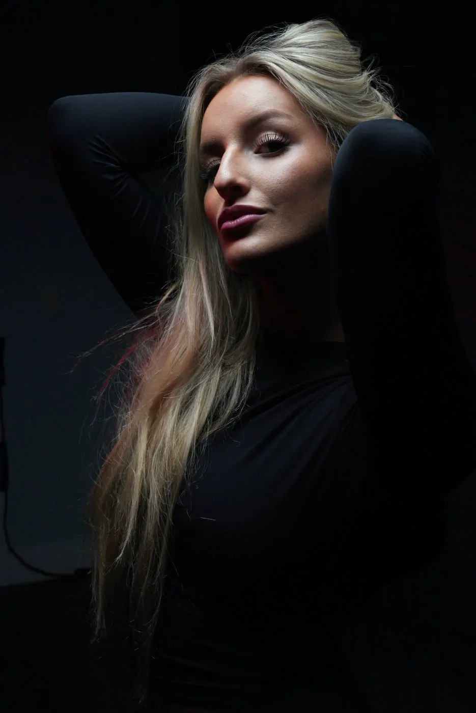 Studio portrait, black background, blonde model, hair down