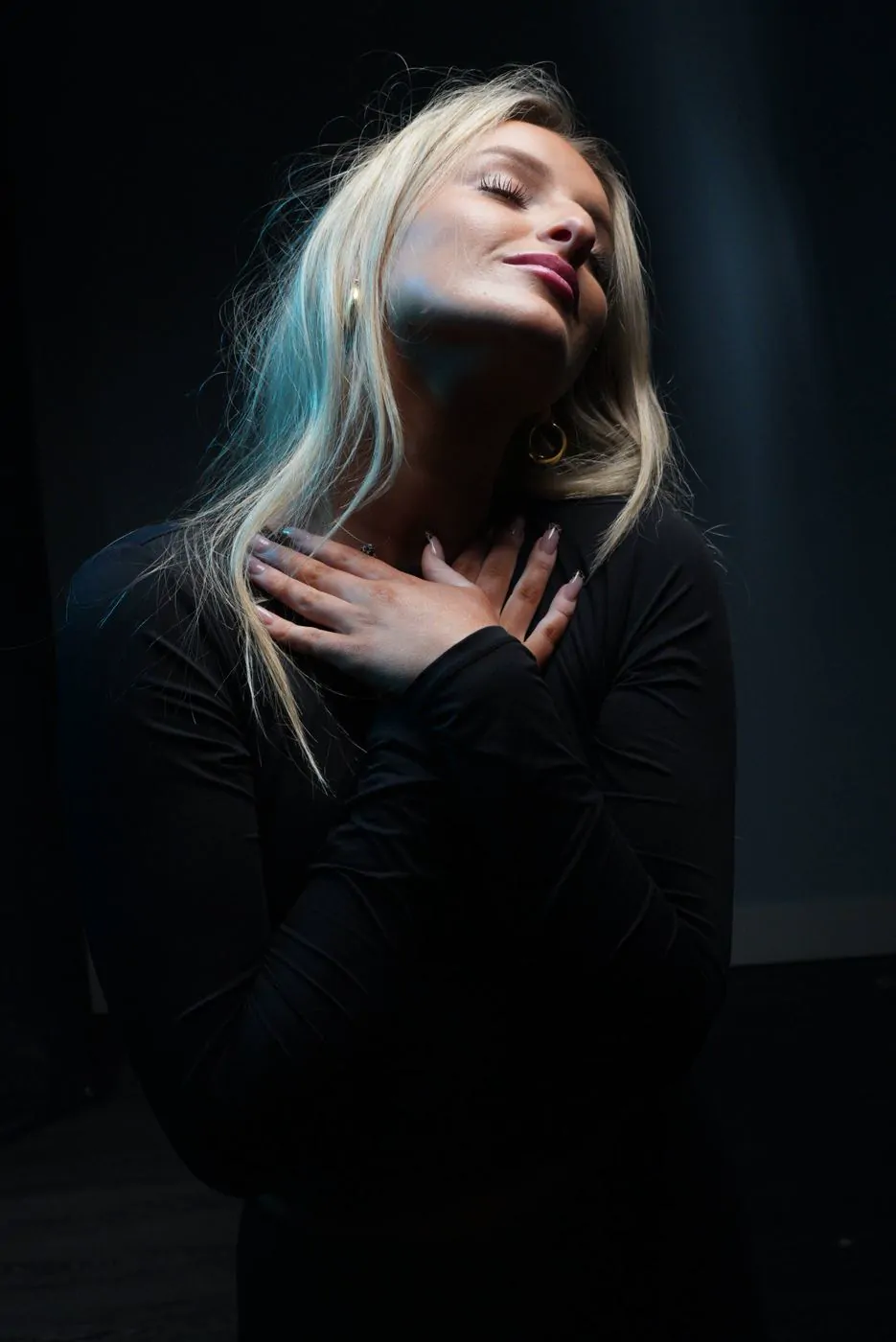 Studio portrait, black background, blonde model